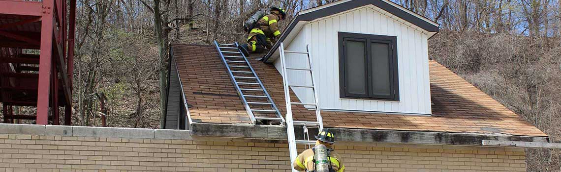 Two Firefighters climbing ladders on house.