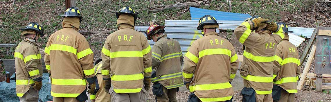 Firefighter recruits training with vehicle extrication equipment.