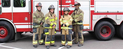 Diversity photo with firefighters in front of fire engine.