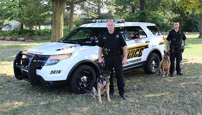 K9 Unit officers and dogs posing in front of K9 unit vehicle.