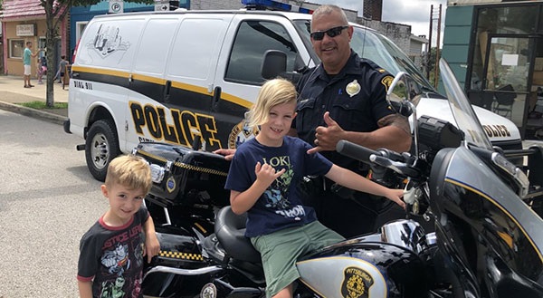 Motocycling officer with young girl citizen sitting on bike.