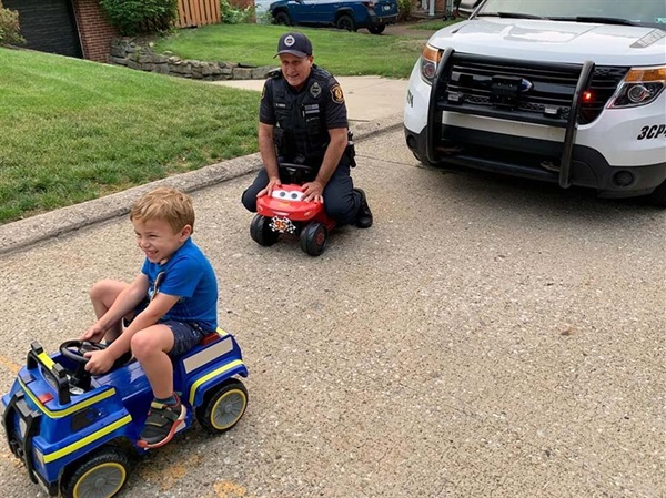 Officer playing with child on riding toys.